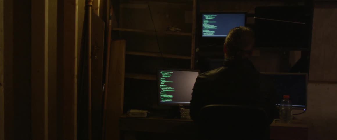 A person works at a desk with three computer monitors