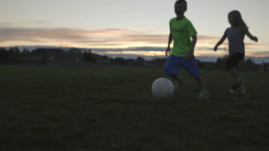 A few kids playing soccer in the park