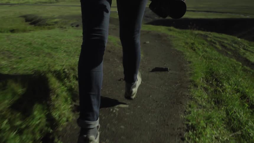 A woman hikes along a dirt path towards the ocean