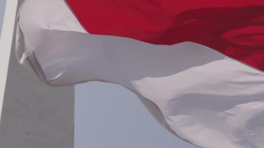 A red and white flag billows in the wind