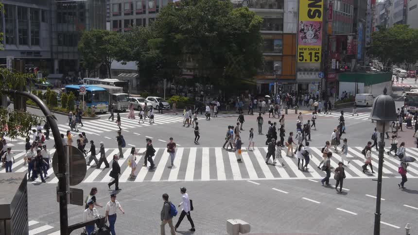 Crowds of people walk across a city street Shibuya Tokyo
