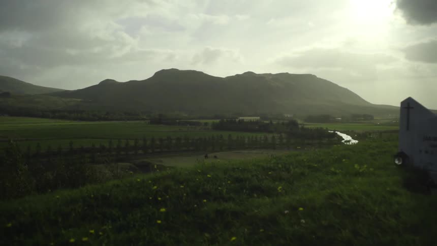 View from the top of a hill of a green field surrounded by trees