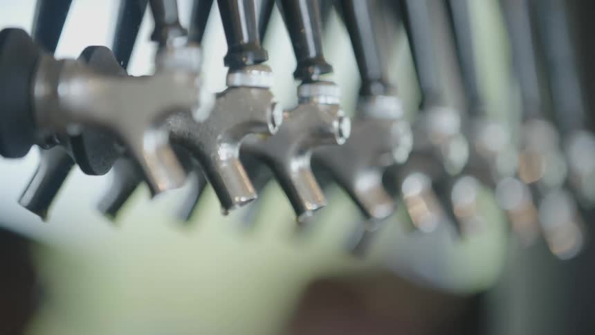 Liquid drips resting on the end of beer taps