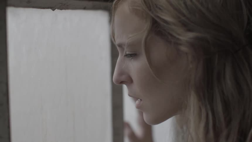 A woman wipes off a window as she looks out