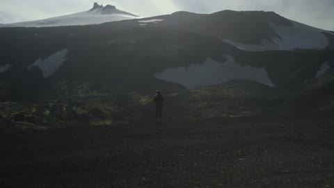 Person standing and looking out at a snowy mountain