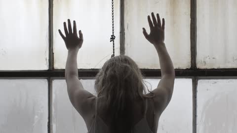 A woman leans against a paned window