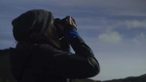 A woman photographs a snow-covered mountain