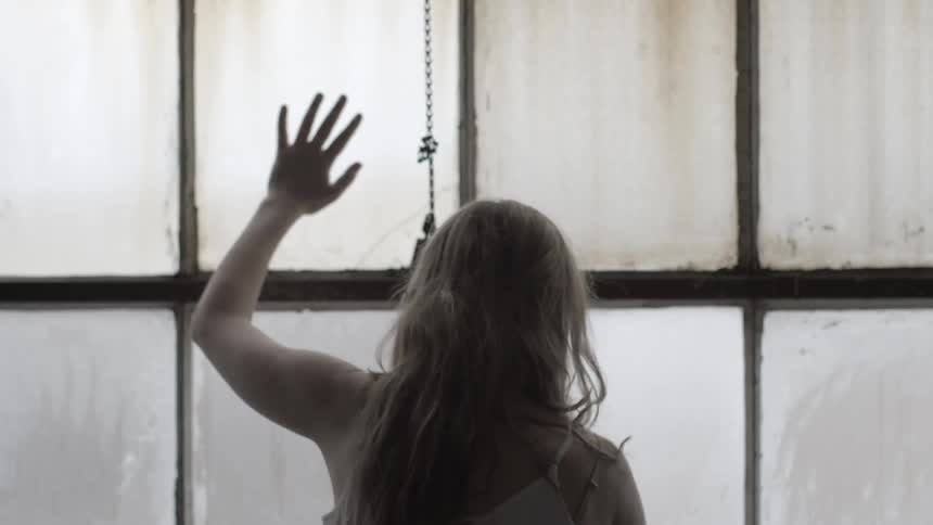 A woman wipes condensation off large windows