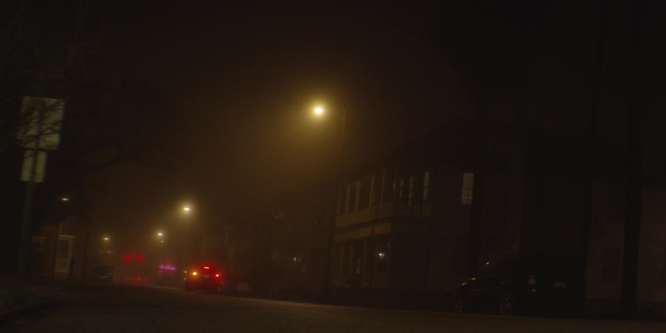 A city street at night with a car driving down it