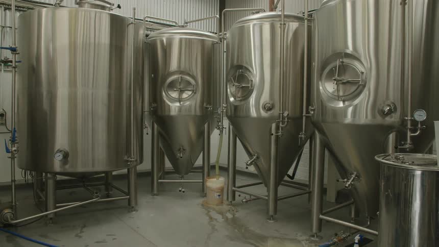 Four stainless steel vats in a shop room