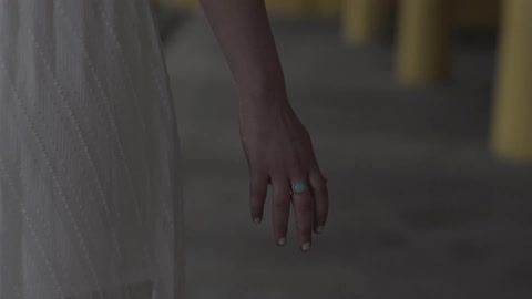 A blonde woman in a white dress and wearing a ring walking