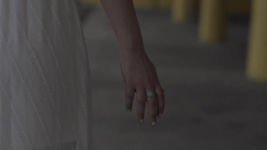 A blonde woman in a white dress and wearing a ring walking