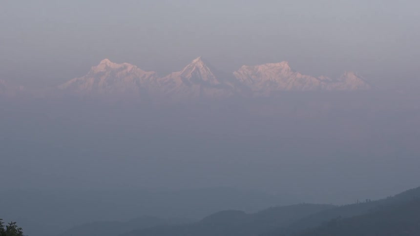 A view of snow-capped mountains rising above clouds