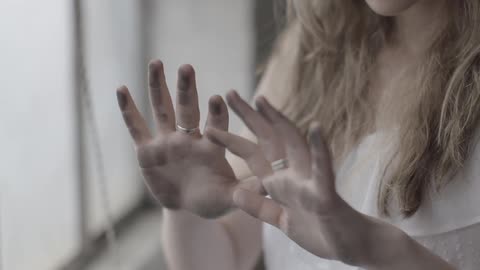 A woman is looking at the dirt on her hands