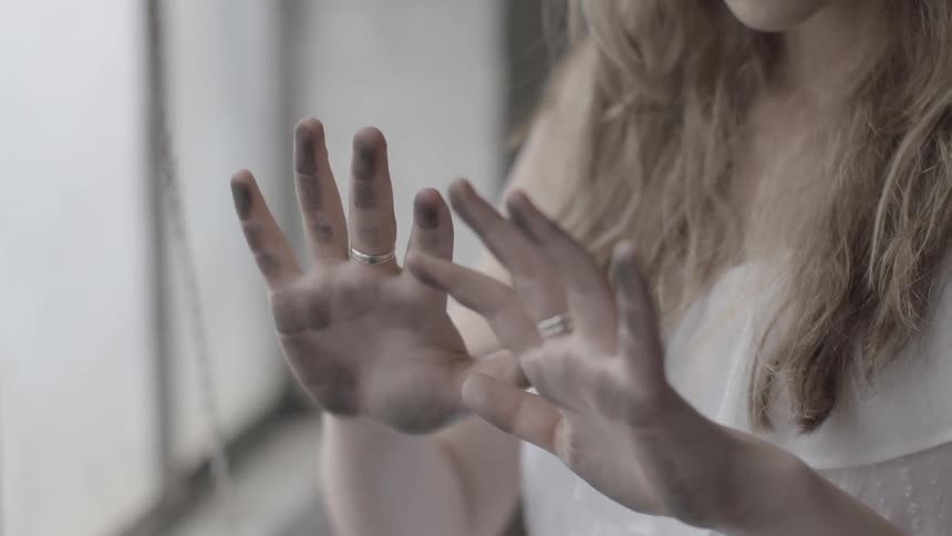 A woman is looking at the dirt on her hands