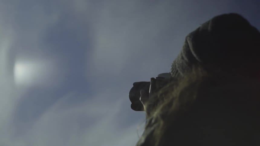 A woman photographs the mountains while the sun shines down brightly