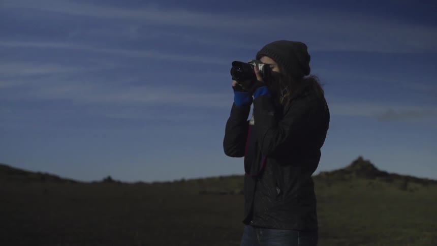 A smiling woman stands taking pictures