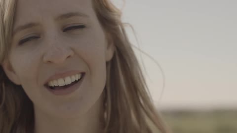A woman smiles and covers her face