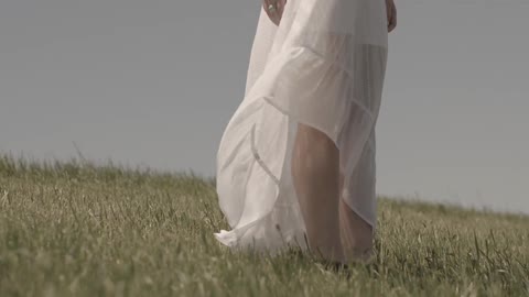 Woman standing in a field wearing a white dress