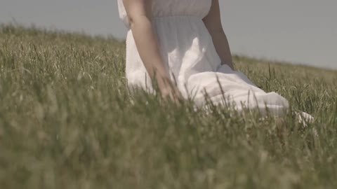 A woman kneels in a grass field