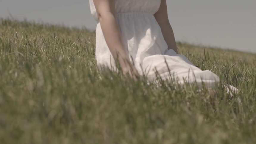 A woman kneels in a grass field