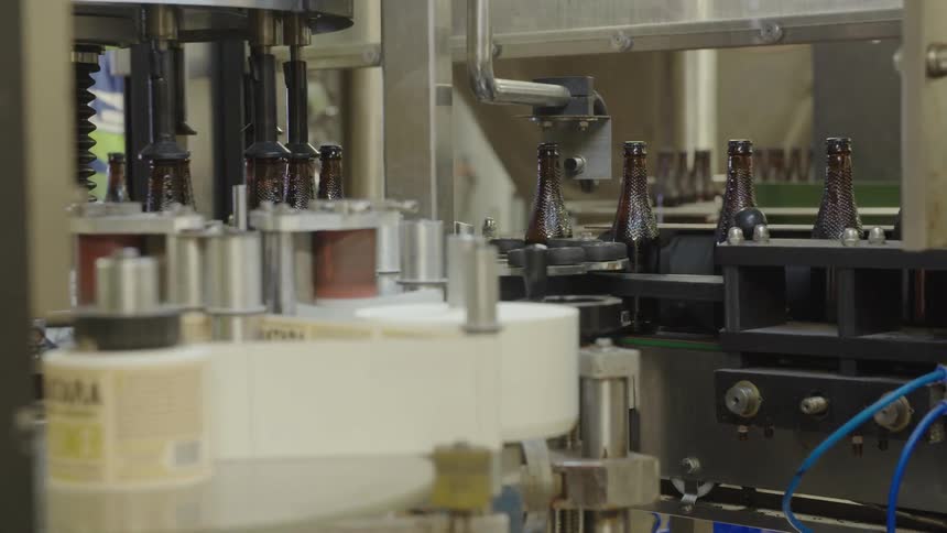 Glass brown bottles move through the assembly line