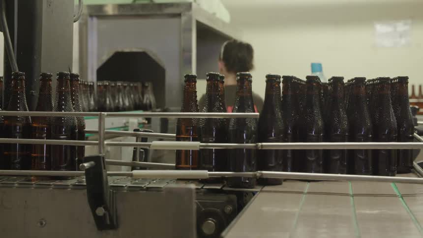Glass bottles move down an assembly line in a factory