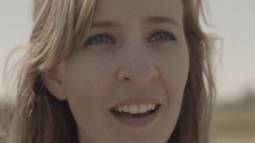 A smiling young woman is watching something
