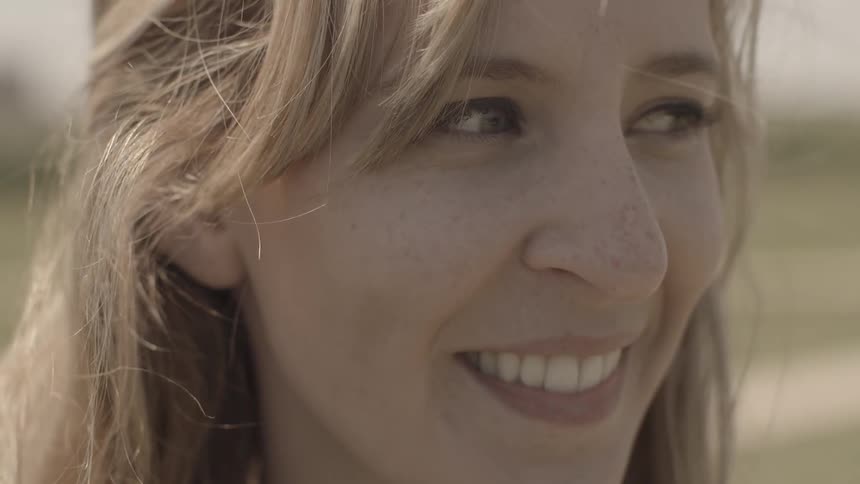 The wind rustles a woman's hair as she smiles