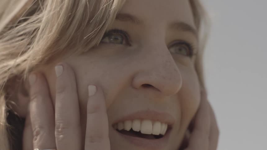 A woman smiles and covers her face in surprise