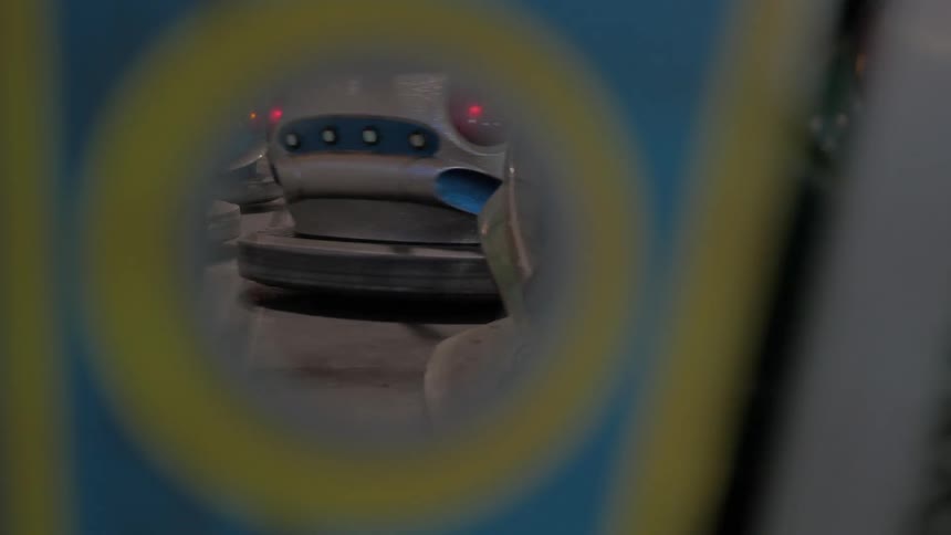 A view of moving bumper cars as seen through a hole