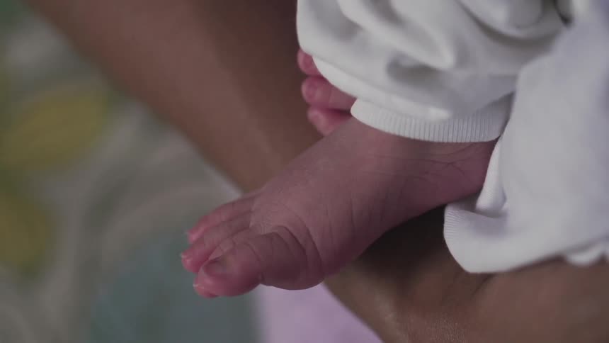 A newborn's feet poke out from white pajamas
