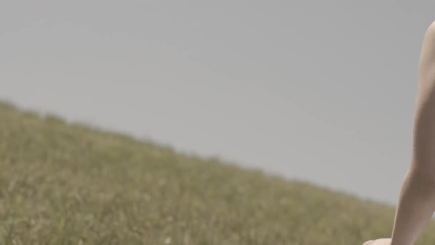 A woman in a white dress running in a field before falling to her knees