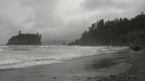 Waves crash against a beach on a foggy evening