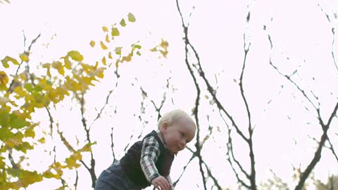 A man playfully tossing his baby in the air outside