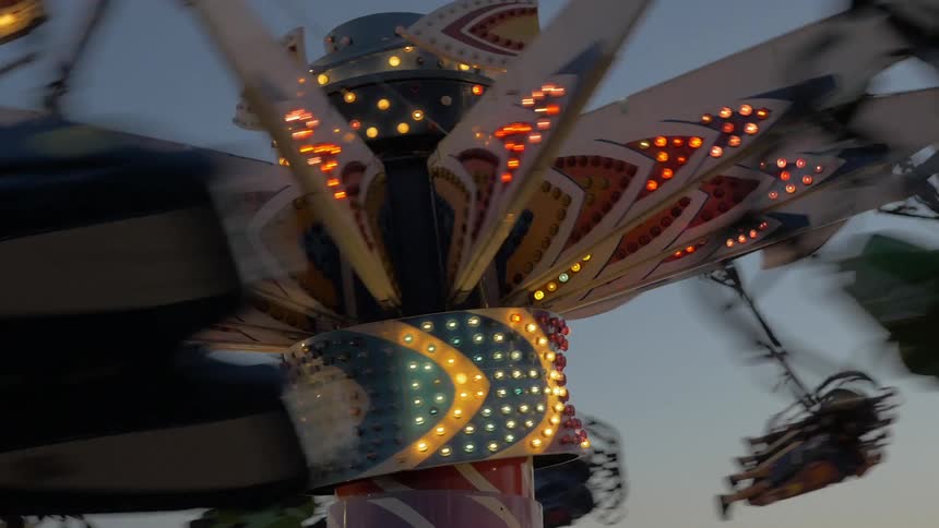 The top of a carnival ride that is lit up and spinning
