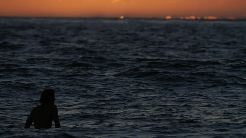 Man swimming in the ocean at sunset