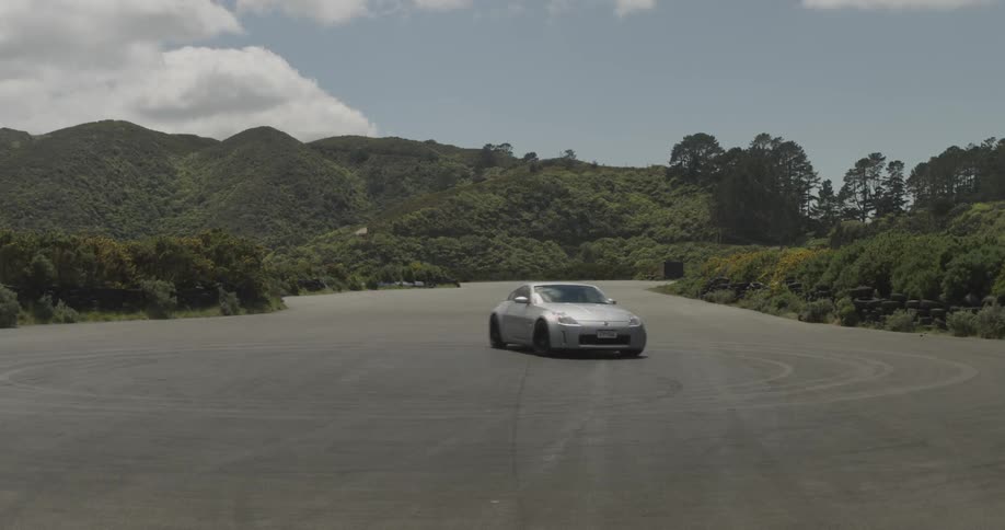A silver sports car does 360s on an empty road