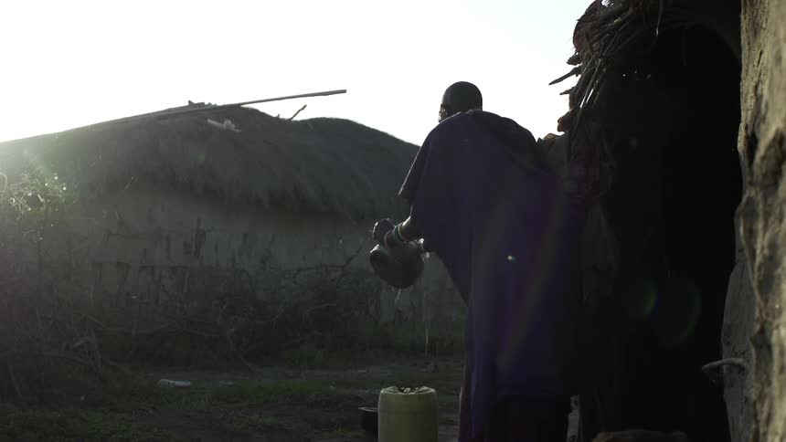 A pot is scrubbed and washed outside in a village