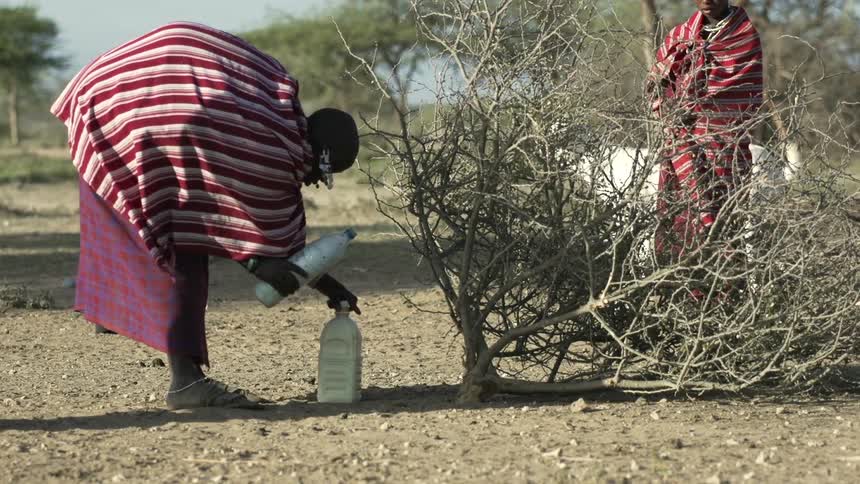A woman pouring water from one jug into another jug