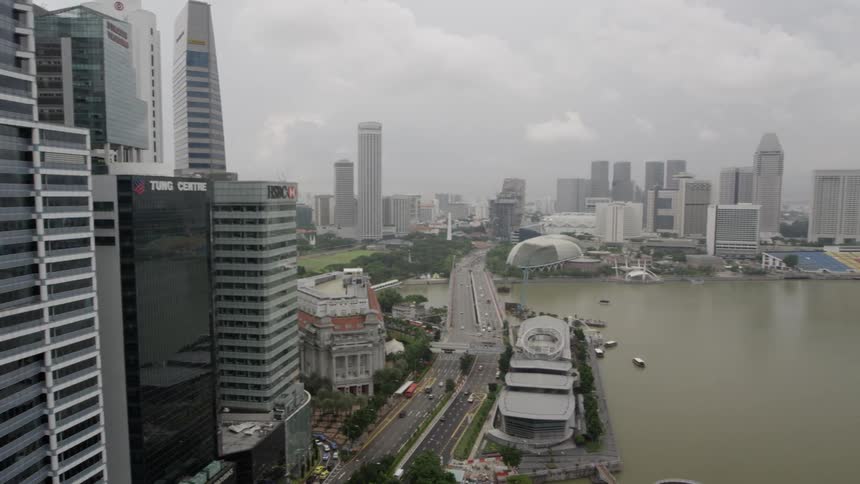 A view of a city on a harbor with tall buildings and traffic on a street