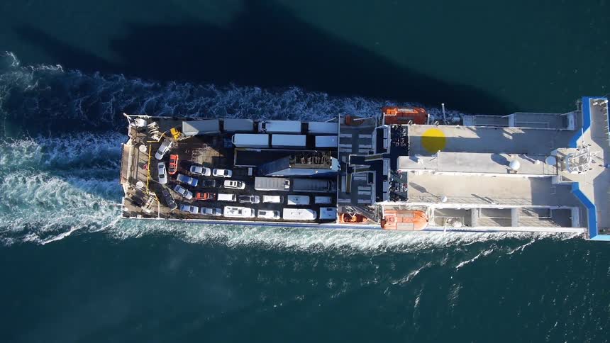A white ferry boat seen from the sky as it sails in the ocean