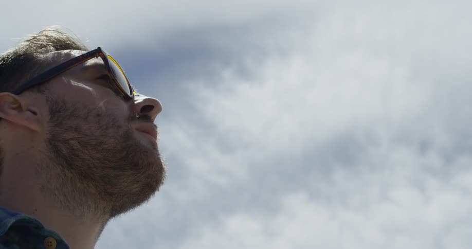 A man looks up into the sunny sky