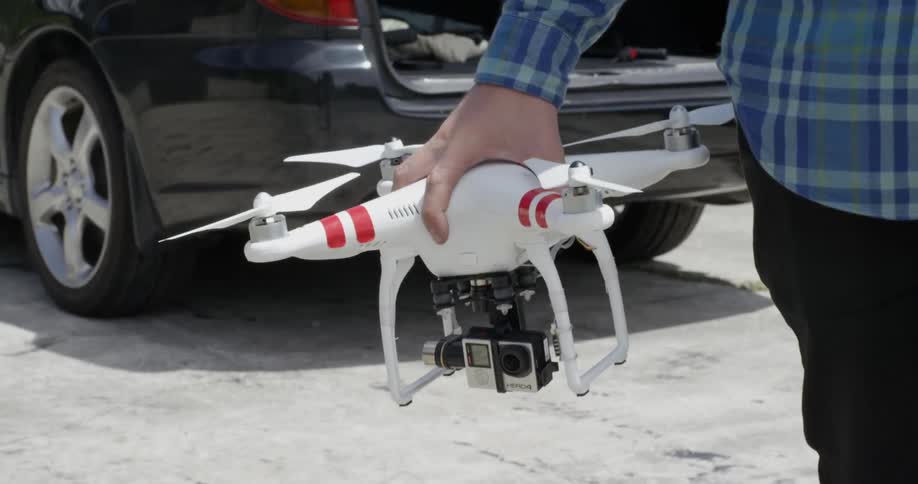 Man carrying a white drone and setting it down on the concrete