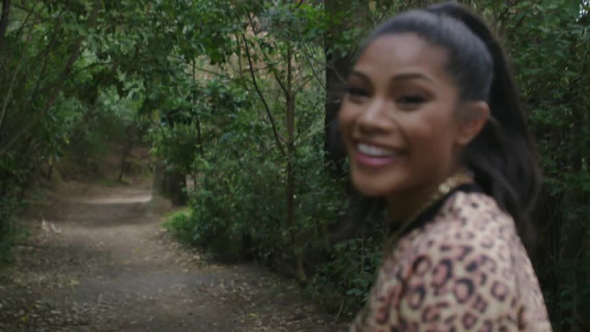 Woman wearing a leopardprint top walking as she turns and smiles into the camera following her
