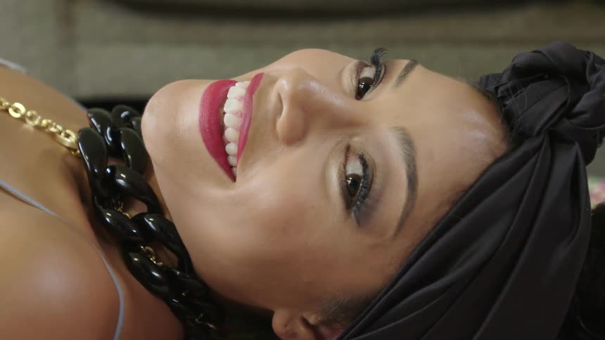 Brunette woman laying on her back, looking towards the camera and smiling