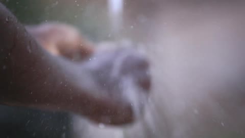 A smiling boy cools his face with water