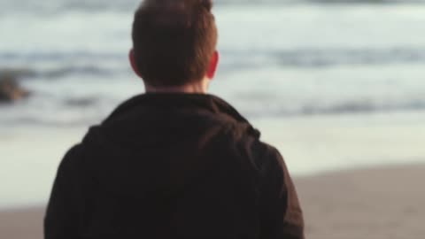 A man walking along a beach towards the water