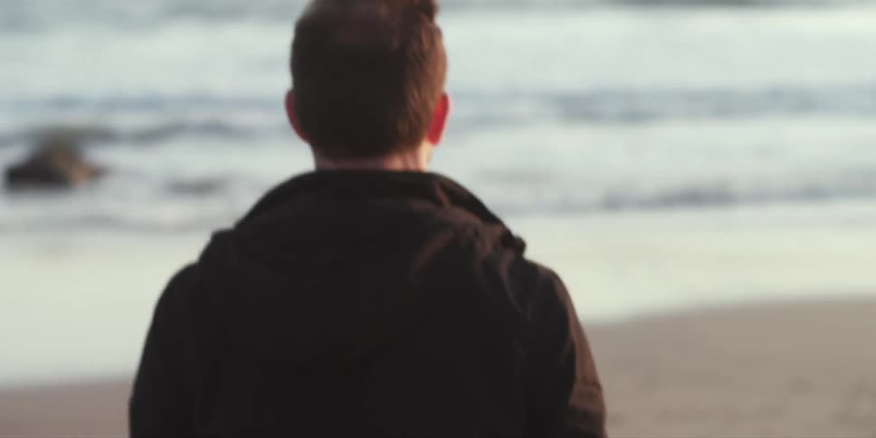 A man walking along a beach towards the water