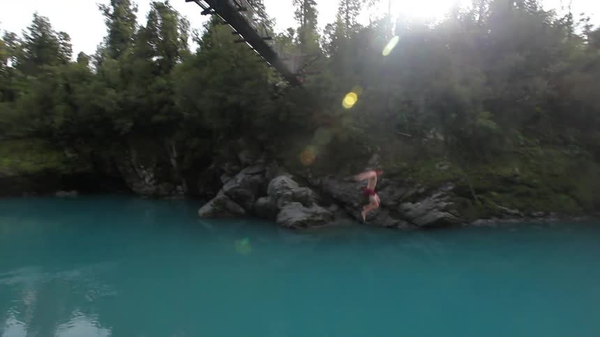 Person jumping from a high bridge into a river